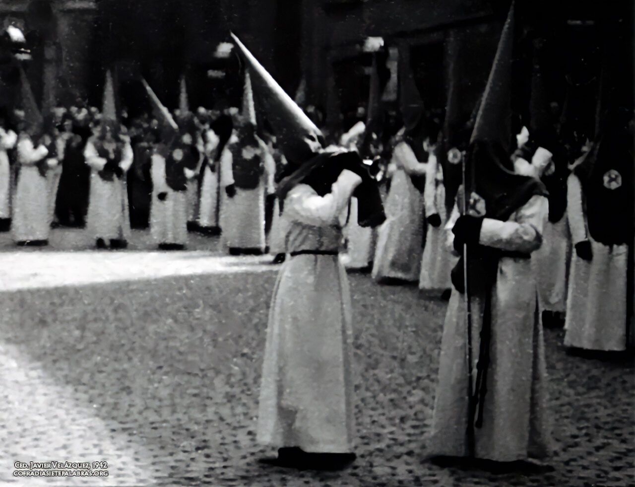 Olegario García Zueco haciendo sonar la corneta en la plaza de Sas durante la procesión matutina del Viernes Santo de 1942, colocándose junto al hermano Cetro de ese año, el Rvdo. Carmelo Coromina (Archivo de Javier Velázquez).